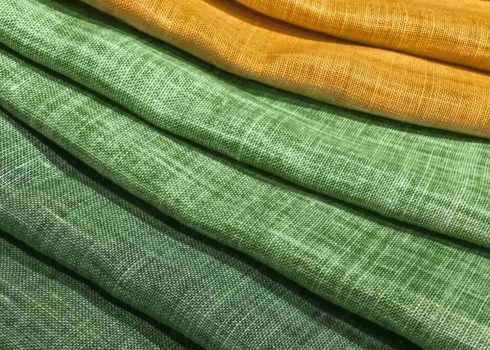 Выбор зеленого и желтого текстиля в магазине тканей.